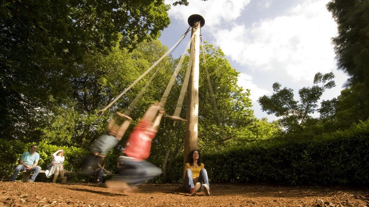 Children playing on the rope swing in the garden at Glendurgan, Cornwall